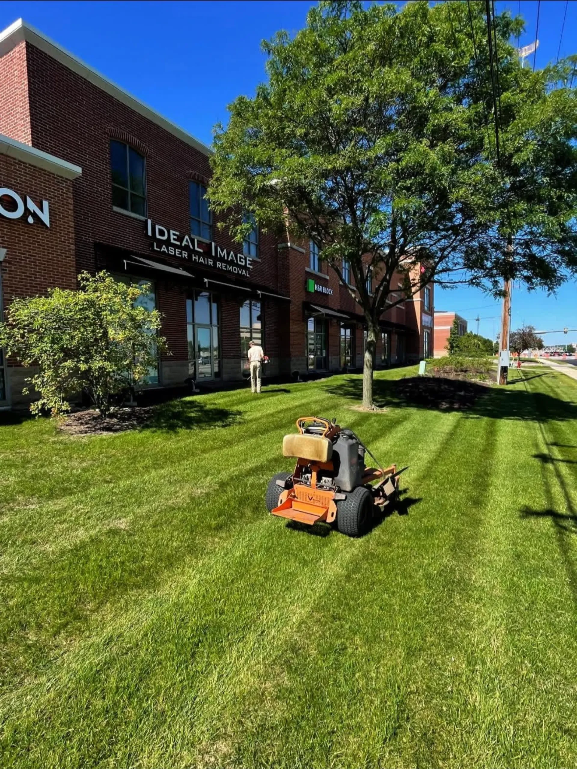 Commercial lawn and landscape maintenance crew mowing, edging, and maintaining a business property in Ixonia, WI.